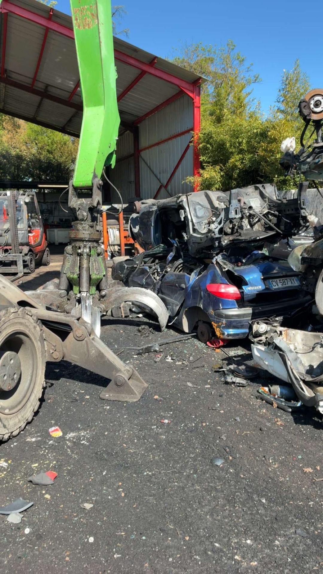 Pince mécanique verte broyant un véhicule en centre VHU agréé Loire